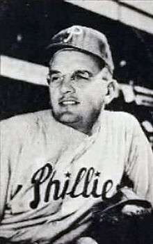 A black-and-white photograph of a man wearing glasses, a dark baseball cap with a white "P" on the front, and a white baseball jersey with "Phillies" across the chest