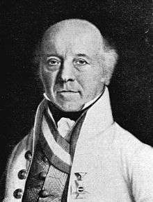 Black-and-white print of a middle-aged bald man in a white, high-collared coat. He has a tuft of hair near each ear and a military award on the breast of his coat.