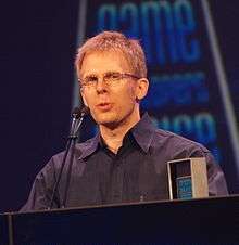 A man giving a speech after receiving an award for lifetime achievement at a game developers conference