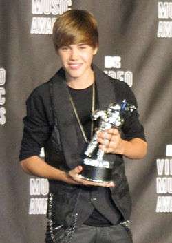 Justin Bieber in 2010 at the VMAs red carpet holding an award.