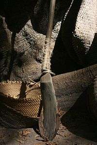 The base of a kayendo with a tree trunk and various wicker products in the background