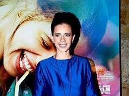 Koechlin smiling at the camera in blue dress