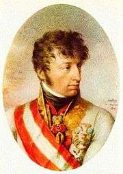 Oval painting of a cleft-chinned young man with wavy brown hair and sideburns. He wears a white military coat with a wide red and white sash over the shoulder.