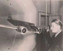 Kelly Johnson facing a model of the Lockheed Model 10 Electra, whose design he worked on. A wind tunnel opening is just behind the model.