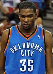 A basketball player, wearing a light blue jersey with the words "OKLAHOMA" and "CITY" and the number 35 on the front, stands on a basketball court.
