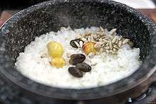Cooked rice sprinkled with four pieces of dried grape and cooked three chestnut in a black stone pot