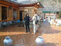 Smiling woman watching a man trying to throw a stick into a pot