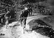 Black and white image of cyclists on a sandy road.