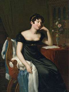 Full-length painted portrait of a woman sitting at a table, writing, and leaning on her hand. There are roses on the table, which is covered with a red, velvet cloth. She is wearing a dark green dress, which reveals her bosom. She has short, brown curls.