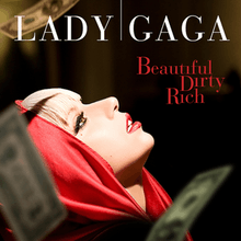 An image of Lady Gaga wearing a red, hooded jacket in front of a black background. Her head is tilted backwards as dollar bills fall around her. At the top of the image, "LADY GAGA" is written in large white text, and below are the words "Beautiful", "Dirty", and "Rich" written in red.