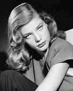 Lauren Bacall in black and white, her head tilted down with her eyes pointed up at the camera