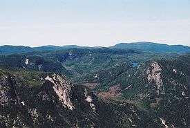 Picture of a green mountain with snow-clad tops.