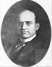 A black-and-white oval portrait of a bald man with spectacles in formal attire.
