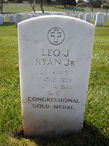 A white-colored tombstone stands in the middle of a cemetery. "Leo J. Ryan Jr" is engraved on it.