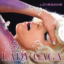 Gaga places her left hand on her forehead and tilts it backwards. The arm is painted in blue and violet colors and glitters are pasted on it.