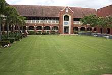 A green quadrangle surrounded by red brick buildings.