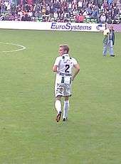 Back view of a fair-haired white man wearing sports kit on a field