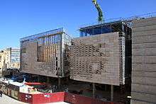 Photo of the Parliament House under construction, with both the steel frame and limestone facade visible