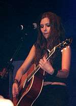 Marion Raven, a young brunette woman, playing a guitar on stage