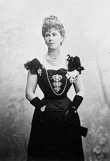 Thin Mary wearing a formal dress, a rope of pearls and a tiara