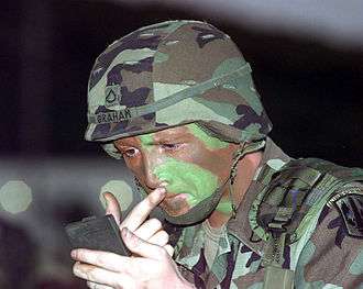 photo of a soldier putting on camouflage face paint