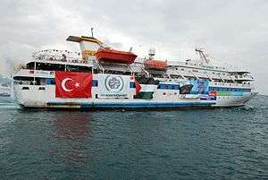Photo of white cruiser yacht, adorned with banners of Turkey and Palestine