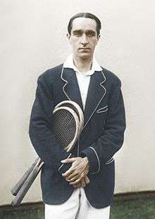 A man in a sports jacket holding two rackets