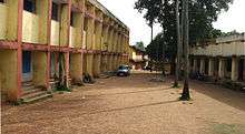 Two buildings, separated by a dirt road and trees