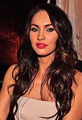 A shot of Megan Fox from the chest up, with dark brown hair.