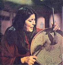 A woman with long black hair playing the percussions.