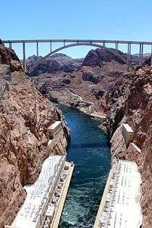 The bridge is silhouetted against the sky with the Colorado river far below