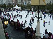 An ice skating rink with dozens of skaters
