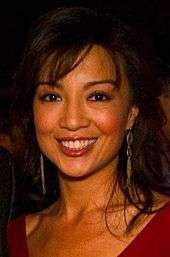 Asian-American woman in a red dress smiling to a camera