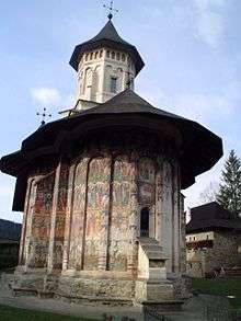 A small chapel in the grounds of a monastery has the walls decorated with four tiers of frescos in rich colours, faded and damaged by the weather. The roof of the chapel overhangs the walls to protect the murals.