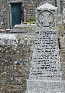 A grey granite monument set into a stone wall of a church