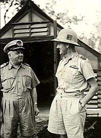 Two men in light-coloured military uniforms, one wearing a pith helmet