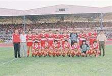 Team photo at a stadium, in front of fans in the stands