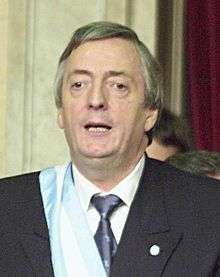 Kirchner speaking, wearing a ceremonial sash