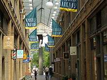 Atrium of a shopping arcade, with green and yellow banners hanging overhead with the words "Nickels Arcade"