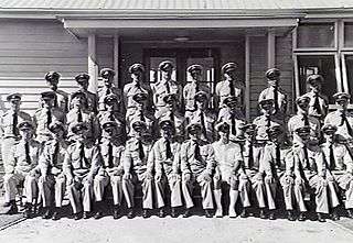 Group portrait of uniformed staff in from of building