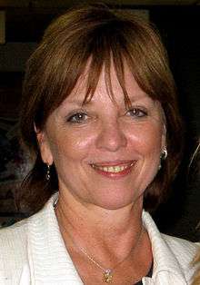 Head and shoulders photo of a middle-aged, smiling woman, with shoulder-length hair