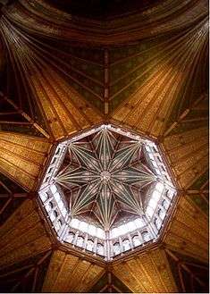 The interior view from beneath an octagonal wooden tower with star shaped vaulting and big windows.