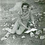 Black-and-white photograph of a woman cataloguing pottery in approximately 1958