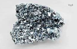 A silvery thumbnail-size chunk of osmium with a highly irregular crystalline surface.