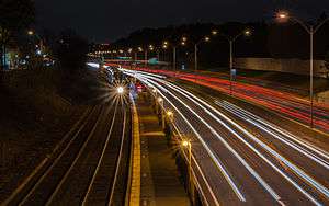 artsy long-exposure of car lights on a highway, with a train