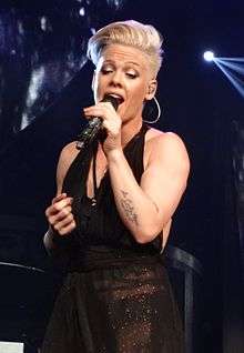 Pink with short platinum hair singing with a microphone