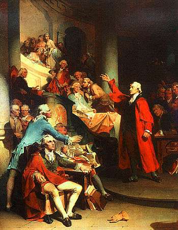 Upper-class middle-aged man dressed in a bright red cloak speaks before an assembly of other angry men. The subject's right hand is raise high in gesture toward the balcony.
