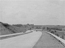 Black-and-white photo of four-lane highway, with one car in each direction