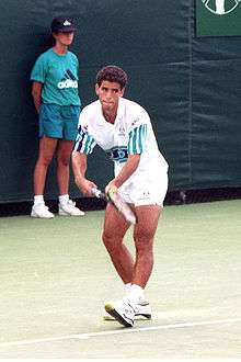 A tennis player holds a racket in his hand and prepares to serve