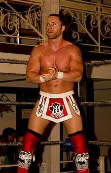 Petey Williams posing in a wrestling ring.